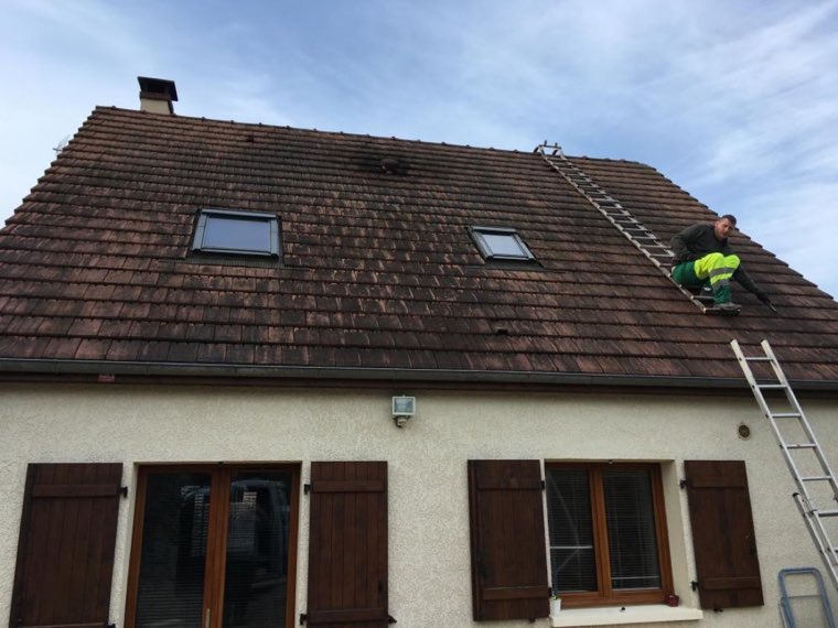 Échelle posée sur une maison de plain-pied, intervention de ramonage en cours