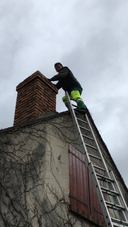 Ramoneur en haut de son échelle, au niveau de la souche de cheminée d'un pavillon