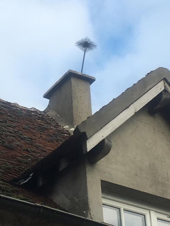 Hérisson de ramonage dépassant du conduit d'une cheminée en cours de ramonage