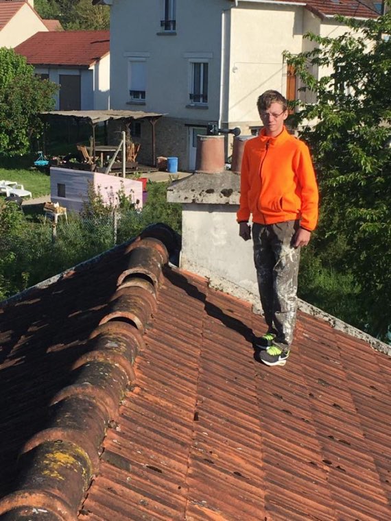 Ramoneur circulant sur le faîtage d'un toit de tuiles pour rejoindre la souche