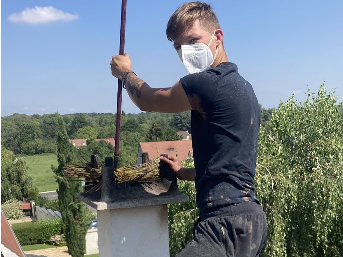 L'artisan Beautour sur un toit en Seine-et-Marne, hérisson de ramonage à la main, en plein ramonage par le haut