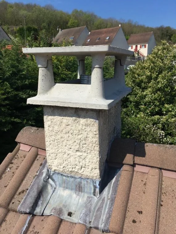 Chapeau de cheminée en béton neuf posé sur une souche, vue depuis le toit