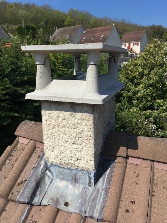 Chapeau de cheminée en béton neuf posé sur une souche, vue depuis le toit