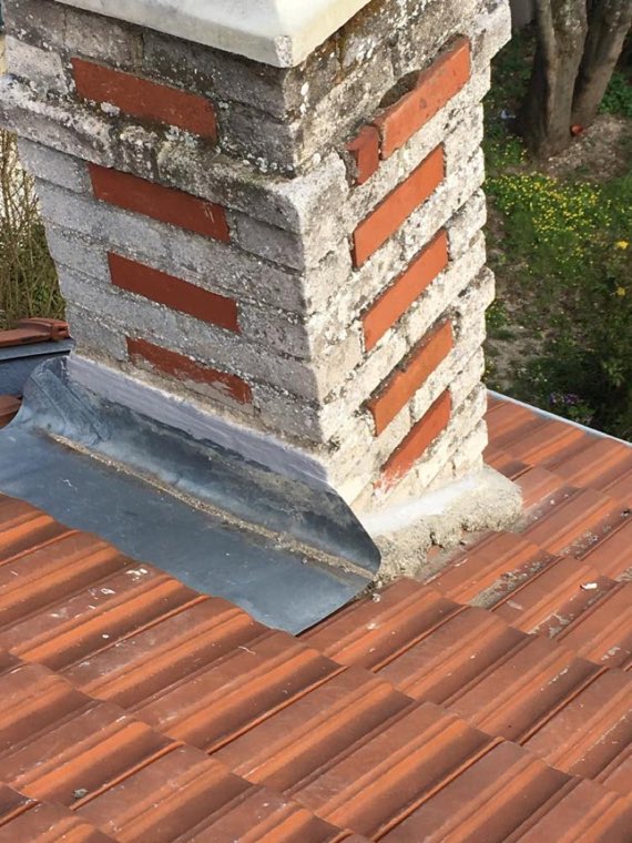Souche de cheminée rejointoyée et solin en zinc neuf posé sur un toit de tuiles